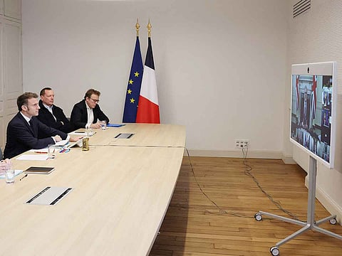 French President Emmanuel Macron attends a videocall as he takes part in a virtual summit held by Britain's PM Keir Starmer (on screen) and focused on peace and security in Ukraine, at the Elysee Palace in Paris on March 15, 2025. Starmer organised the virtual summit gathering some 25 leaders to discuss a possible coalition willing to protect any eventual ceasefire in Ukraine.