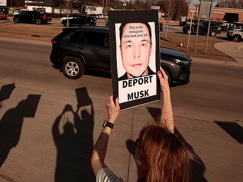People participate in a protest against Elon Musk outside of a Tesla dealership in West Bloomfield, Michigan on March 13, 2025.