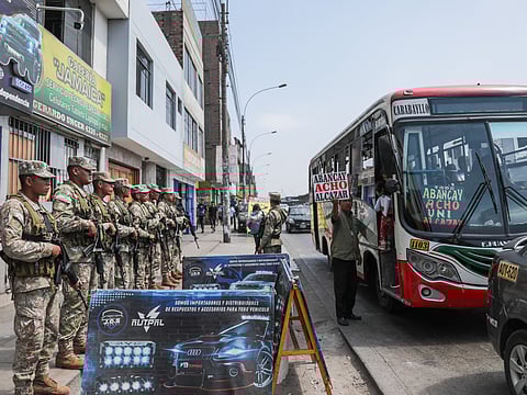 Military forces stand guard at a bus stop near the the Naranjal Metropolitano transport station in Lima