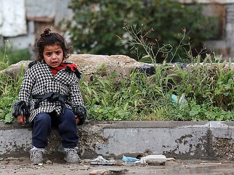 A young girl sits crying on the side of a road as Palestinians flee with their belongings Beit Lahia in the Northern Gaza Strip on March 21, 2025. AFP