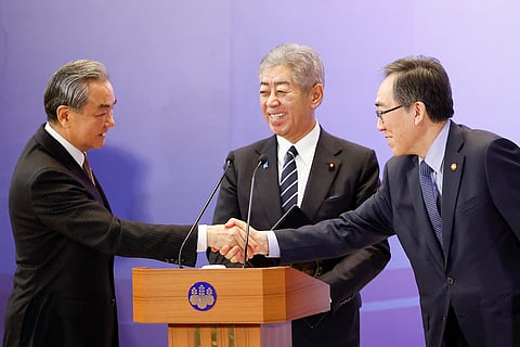 China's Foreign Minister Wang Yi (L) and South Korea's Foreign Minister Cho Tae-yul (R) shake hands as Japan's Foreign Minister Takeshi Iwaya looks on during a joint press conference after their meeting during the 11th Trilateral Foreign Minister's Meeting (Japan-China-ROK) in Tokyo on March 22, 2025.