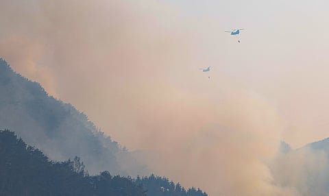 Helicopters try to extinguish a fire after a wildfire broke out in the southeastern county of Sancheong on March 22, 2025.