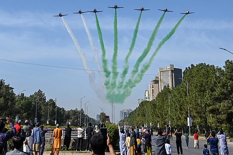People watch as the Pakistan Air Force Karakoram-8 (K-8) aircraft team performs aerobatic manoeuvres during the National Day parade as they fly past near the President's House in Islamabad on March 23, 2025