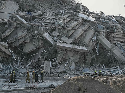 Rescue workers walk past debris of a construction site after a building collapsed in Bangkok on March 28, 2025, following an earthquake.