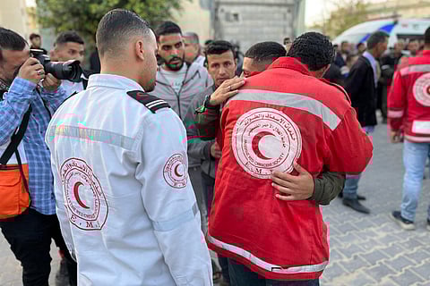 A paramedic embraces a youth as the bodies of Palestinian first responders, who were killed a week before in Israeli military fire on ambulances, arrive at Nasser Medical Complex in Khan Yunis in the southern Gaza Strip on March 30, 2025.