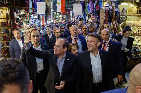 Egyptian President Abdul Fattah Al Sissi greets people as he walks alongside his French counterpart Emmanuel Macron during a stroll at the Khan al-Khalili market area in Cairo.
