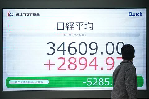 A man looks at an electronic board showing the closing numbers of the Nikkei Stock Average on the Tokyo Stock Exchange in Tokyo on April 10, 2025.