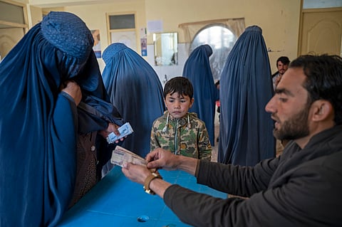 An Afghan woman receives cash money being distributed as an aid by the World Food Programme (WFP) organisation in Pul-i-Alam, the provincial capital of Logar Province.