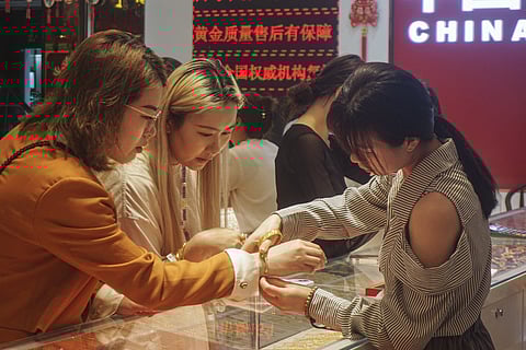 Customers try gold jewellery at a gold shop in Hangzhou, in eastern China's Zhejiang province on April 22, 2025.