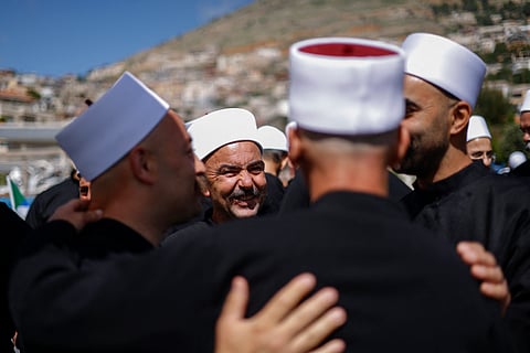 Druze clerics welcome visitng counterparts who just arrived from Syria in a bus through a border barrier guarded by Israeli soldiers, in the village of Majdal Shams in the Israeli-annexed Golan Heights, on April 25, 2025.