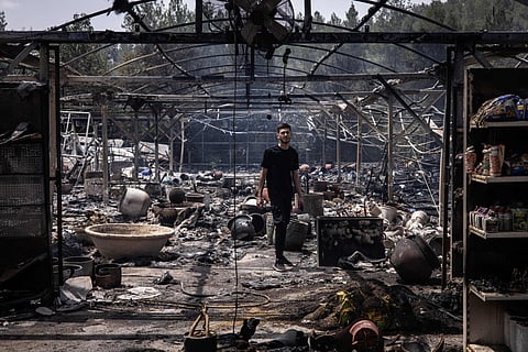 A man walks through a burnt garden shop in Mesilat Zion in central Israel, on May 1, 2025. Israeli firefighting teams battled wildfires near Jerusalem for a second day on May 1, with police reporting the reopening of several major roads that had been closed.