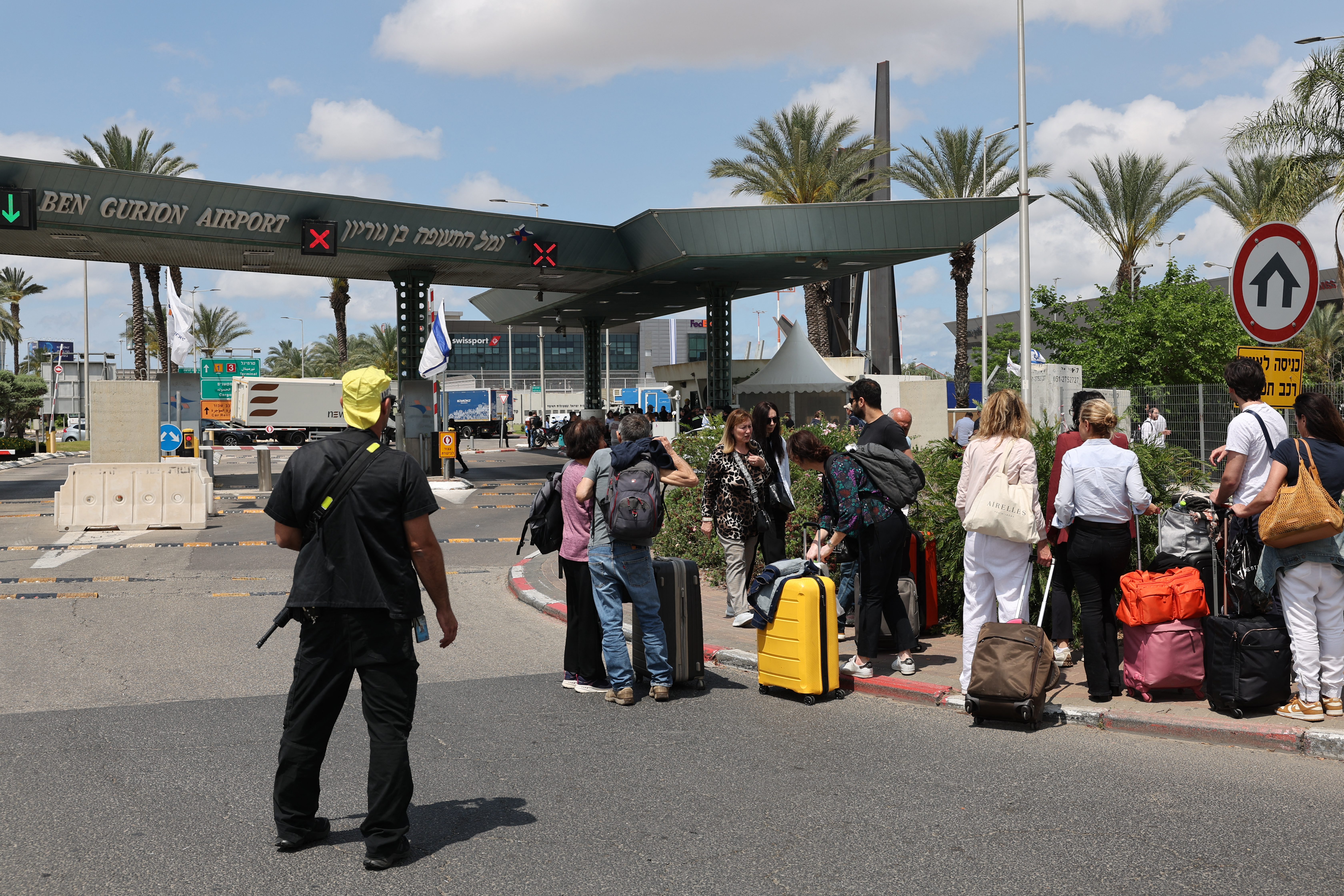 Travellers wait by their luggage outside Israel's Ben Gurion airport as flights are interrupted after the country activated air defences against a missile launched from Yemen on May 4, 2025.