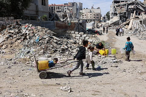 Palestinian children head to a water distribution point to fill their containers in Gaza City on May 4, 2025.