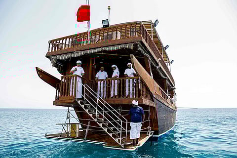 Participants pose while riding aboard a traditional dhow boat cruising in the Gulf waters during the handline fishing competition of the Senyar Festival off of Sealine south of Doha.