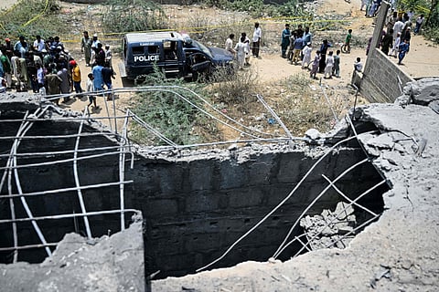 Residents gather as police personnel inspect the site where an alleged drone was shot down in Karachi on May 8, 2025.