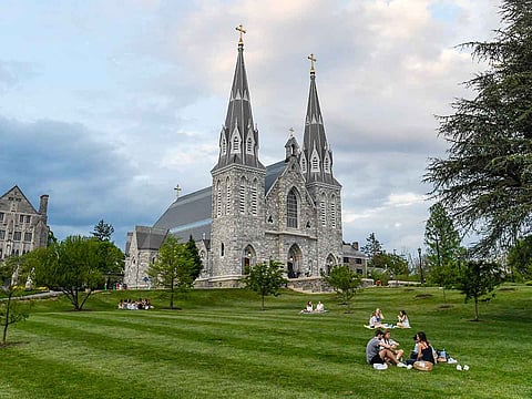 Students sit on the lawn outside of St. Thomas of Villanova Church at the campus of Villanova University in Villanova, Pennsylvania.