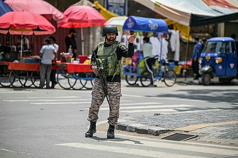 An Indian paramilitary soldier gestures as he stands guard along a street in Srinagar on May 11, 2025.