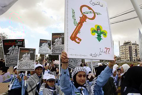 Palestinians carry posters during a rally to commemorate the 77th anniversary of the "Nakba" in the city of Ramallah in the occupied West Bank.