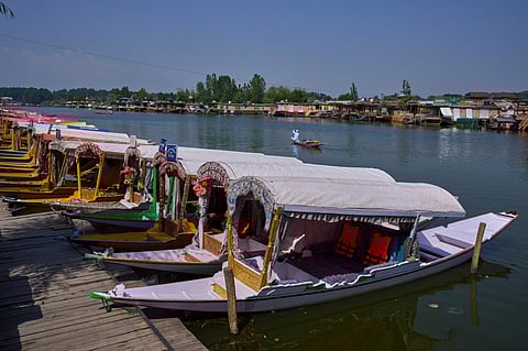 A Kashmiri flower vendor rows past anchored Shikaras, or traditional wooden boats, on Dal Lake in Srinagar on Tuesday.