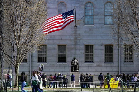 Demonstrators with signs stand around the John Harvard Statue following a rally against President Donald Trumps attacks on Harvard University at the university in Cambridge, Massachusetts, on April 17, 2025.