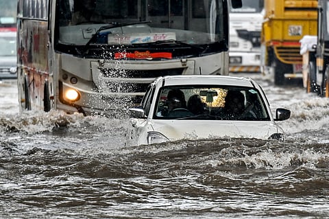 A car lies partially submerged as it wades through a flooded street after heavy rain showers in Mumbai.