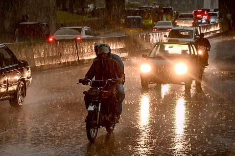 Commuters ride along a street as it rains in the Peshawar district of the Khyber Pakhtunkhwa province of Pakistan on May 27, 2025.