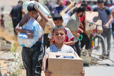 A boy carries a box of relief supplies from the Gaza Humanitarian Foundation (GHF), a private US-backed aid group that has bypassed the longstanding UN-led system in the territory, as displaced Palestinians return from an aid distribution centre in the central Gaza Strip on May 29, 2025.