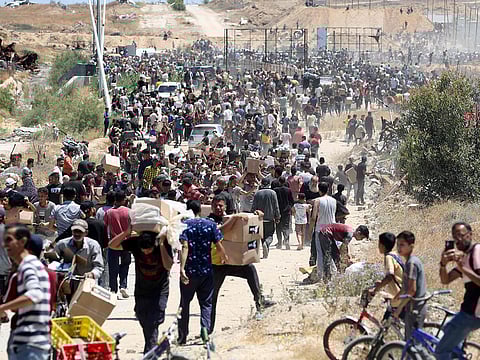 People carry boxes of relief supplies from the Gaza Humanitarian Foundation (GHF), a private US-backed aid group that has bypassed the longstanding UN-led system in the territory, as displaced Palestinians return from an aid distribution centre in the central Gaza Strip on May 29, 2025.
