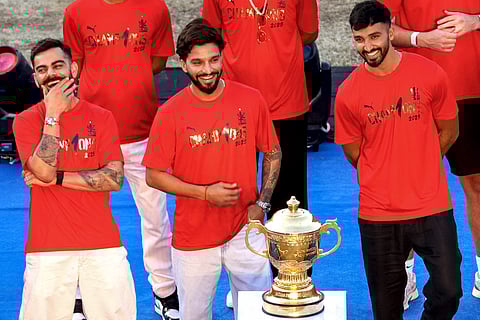 Royal Challengers Bengaluru's Virat Kohli (left) and captain Rajat Patidar (centre) and Jitesh Sharma stand beside the Indian Premier League trophy during celebrations at M. Chinnaswamy Stadium in Bengaluru.