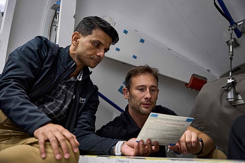 This handout photograph taken on September 6, 2024 and released by private aerospace company Axiom Space shows assigned Ax-4 crew members Shubhanshu Shukla (left) and Slawosz Uznanski reviewing a procedure checklist card during training within the ISS Harmony module mockup.