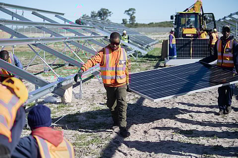Workers carry solar panels to be fitted onto frames during construction at South Africa’s first municipally owned solar plant, during International World Environment Day, on June 05, 2025, in Atlantis, about 40km from Cape Town.
