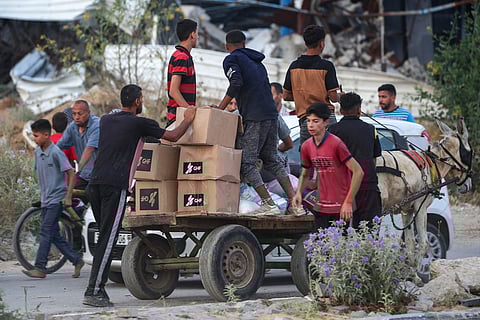 People transport relief supplies on a cart from the Gaza Humanitarian Foundation (GHF), a private US-backed aid group that has bypassed the longstanding UN-led system in the territory, as displaced Palestinians return from an aid distribution centre in the central Gaza Strip on June 8, 2025.