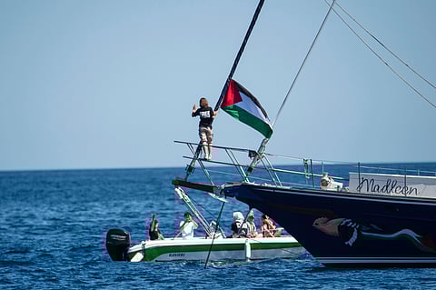 Climate activist Greta Thunberg stands near a Palestinian flag after boarding the Madleen boat and before setting sail for Gaza along with activists of the Freedom Flotilla Coalition, departing from the Sicilian port of Catania, Italy, Sunday, June 1, 2025.