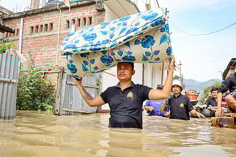 A man carries a mattress as he wades through floodwaters at Kongba in Imphal East on June 3, 2025.