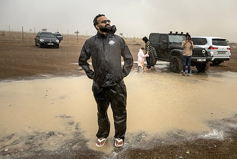 Mohammed Sajjad, known locally as "The Weatherman" (C) stands in the rain with others who took part in a "rain chase" in the emirate of Sharjah on June 7, 2025.