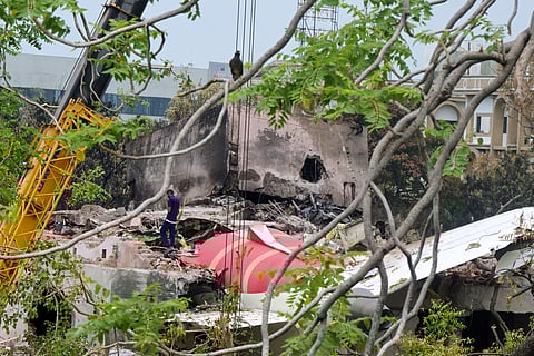 A crane removing aeroplane's tail from the wreckage after the June 12 Air India flight 171 crash, is pictured in a residential area near the airport in Ahmedabad on June 14, 2025.