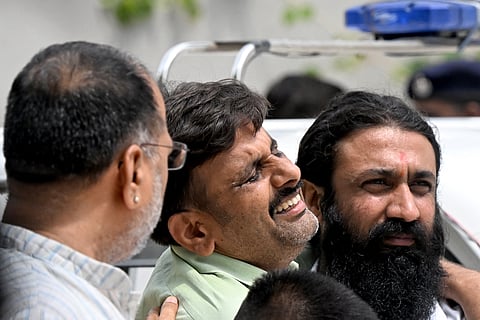 A family member (C) mourns the death of an Air India flight crash victim as he arrives to collect mortal remains outside a hospital mortuary in Ahmedabad on June 15, 2025.