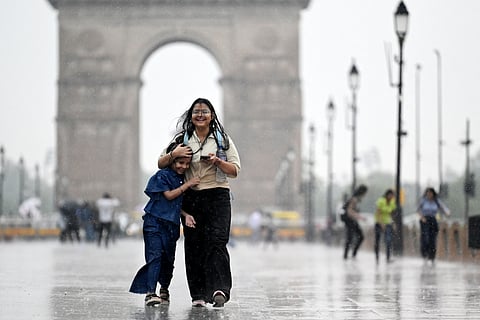 Girls walk along a road at the India Gate as it rains in New Delhi on June 17, 2025. Delhi is expected to use cloud seeding this week, hoping the artificial rain can help alleviate the impact of key pollutants like dust and smog.