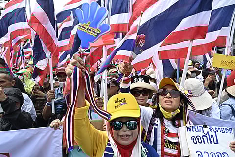 Anti-government protesters hold Thai national flags during a demonstration to demand the removal of Thailand's Prime Minister Paetongtarn Shinawatra from office outside Government House in Bangkok on June 19, 2025.