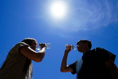 FILE - Tony Berastegui Jr., right, and his sister Giselle Berastegui drink water, July 17, 2023, in Phoenix.