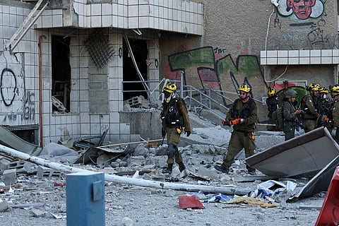 Israeli first responders walk near a building that was hit by an Iranian strike in Haifa on June 20, 2025, amid the ongoing fire exchange between Israel and Iran.