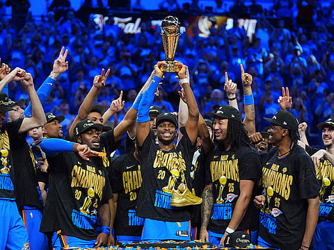 Oklahoma City Thunder guard Shai Gilgeous-Alexander, center, holds up the MVP trophy as he celebrates with his team after they won the NBA basketball championship with a Game 7 victory against the Indiana Pacers Sunday in Oklahoma City.