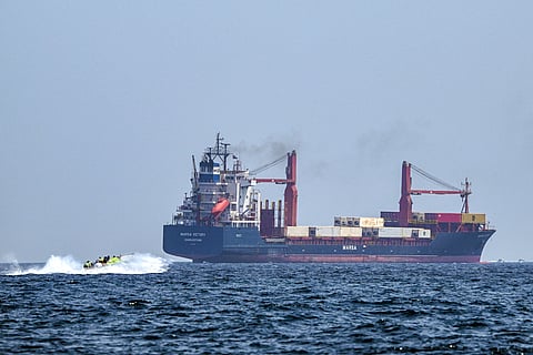 A boat approaches the container ship Marsa Victory while cruising in the waters of the Strait of Hormuz off the coast of Khasab in Oman’s northern Musandam peninsula. File photo taken on June 25, 2025.