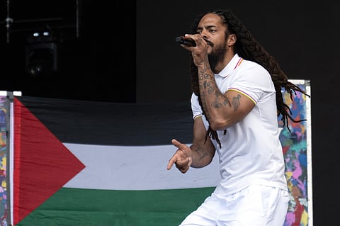 To the backdrop of a Palestinian flag, Bobby Vylan of British duo Bob Vylan performs on the West Holts Stage on the fourth day of the Glastonbury festival at Worthy Farm in the village of Pilton in Somerset, south-west England, on June 28, 2025.