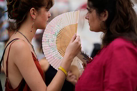 Demonstrators use fans to help with the high temperature during a protest against the housing crisis affecting Portugal, in Lisbon, Saturday, June 28, 2025.