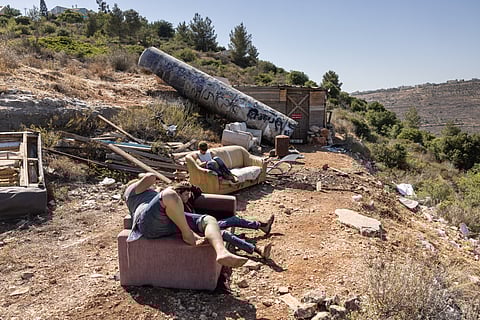 People sit next to remains of an Iranian missile that fell at the settlement of Neria near Ramallah, in the occupied West Bank, on 29 June 2025, in the aftermath of the 12-day war between Israel and Iran.