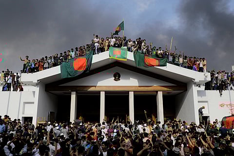 Anti-government protestors display Bangladesh's national flag as they storm Prime Minister Sheikh Hasina's palace in Dhaka on August 5, 2024.