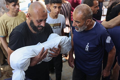 A man carries the body of a child at al-Shifa hospital in Gaza City, where the victims of an Israeli strike which hit the Mustafa Hafez school, sheltering Palestinians displaced by the war, were brought, on July 3, 2025, amid the ongoing conflict between Israel and the Palestinian Hamas militant group.