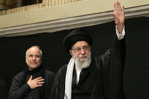 This handout picture released by the office of Iran's Supreme Leader Ayatollah Ali Khamenei on July 5, 2025 shows him (R) waving to the audience during a mourning ceremony in Tehran marking the ninth day of the Islamic month of Muharram.