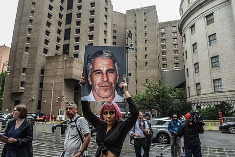 A member of a protest group called "Hot Mess" holds up a sign of Jeffrey Epstein in front of the Metropolitan Correction Center on July 8, 2019 in New York City.
